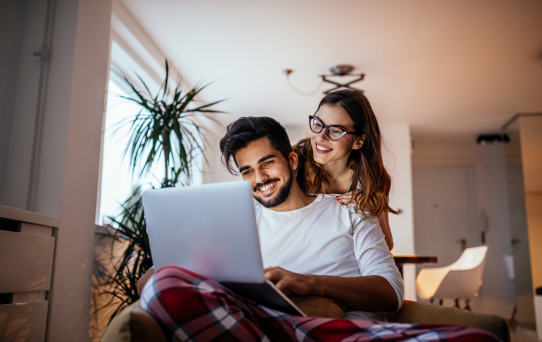Casal utilizando notebook em casa com internet residencial estável, representando conexão disponível em Curitiba e região metropolitana.