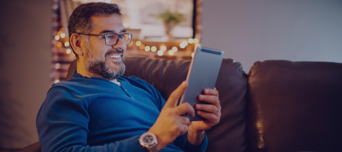 Homem utilizando tablet em casa, representando uma internet residencial rápida, estável e ideal para o dia a dia.